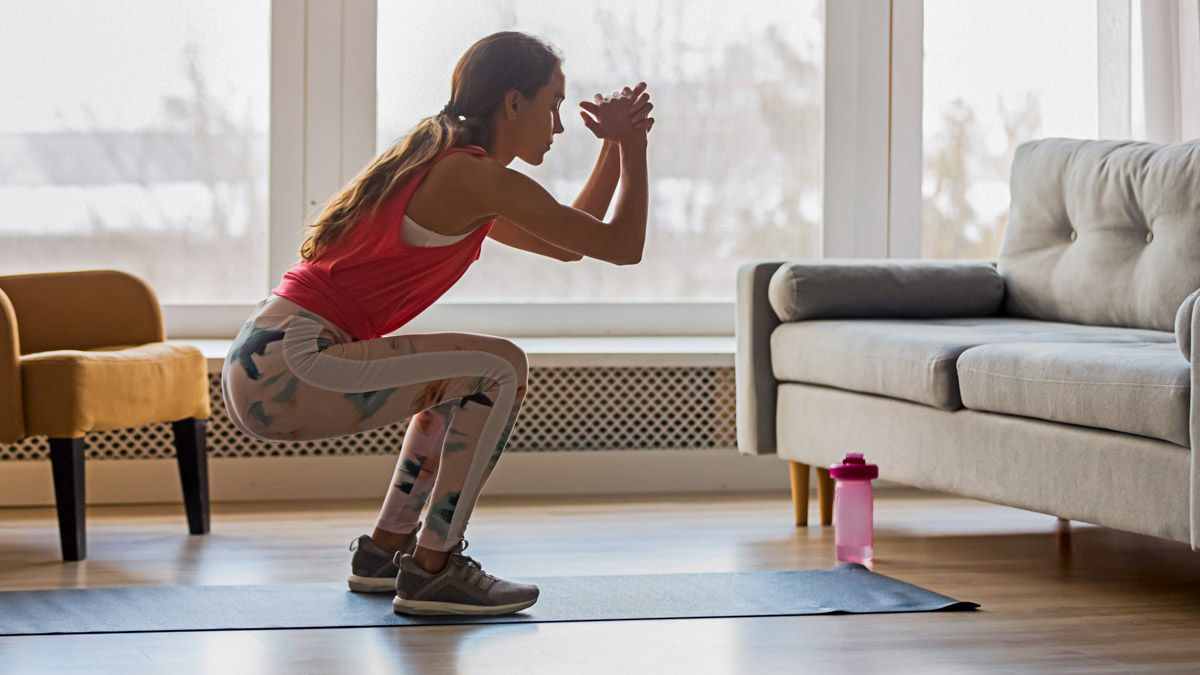 Sporty Young Woman Doing Squat Morning Exercise In Living Room Sporty Young Woman Doing Squat Morning Exercise In Living Room