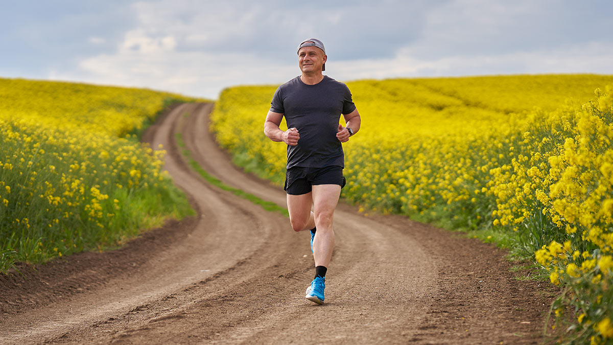 How To Improve Your Running From Runner Man Running Down Dirt Path In Shorts Ad Tshirt With Good Running Form On A Sunny Day