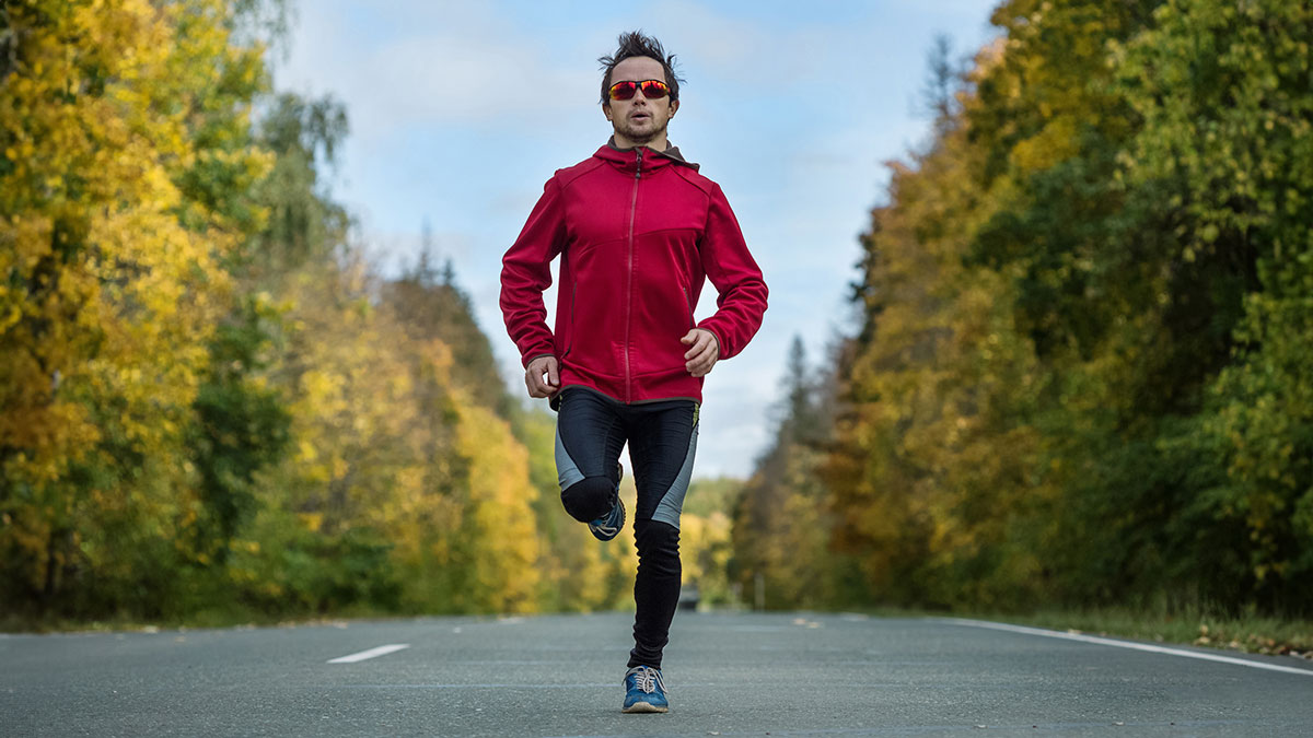 Running Man Running Down A Paved Street Outside On Sunny Day Doing A Fartlek Workout