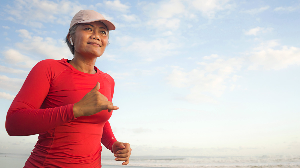 A Female Athlete’s Guide To Hormone Replacement Therapy Image Of An Older Asian Woman Who's Taken Hormone Replacement Therapy Running On The Beach