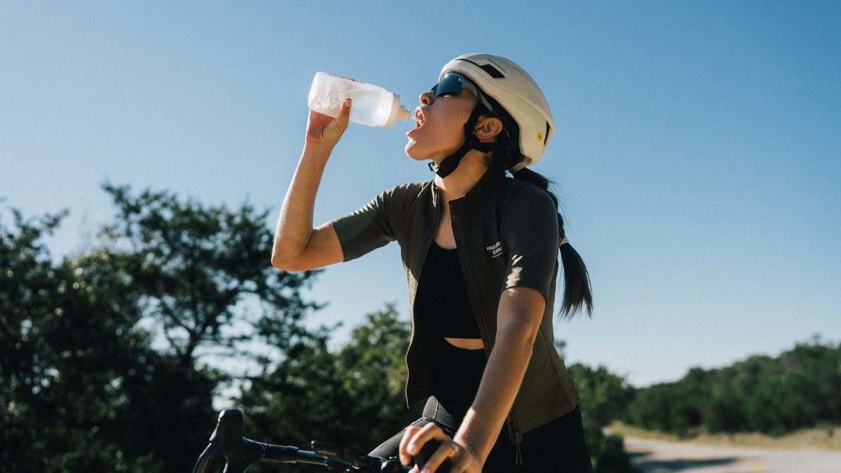 Woman Taking A Break While Cycling In The Heat, Drinking Water To Maintain Optimal Hydration Levels.