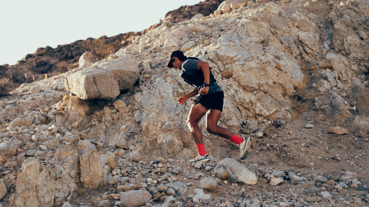 Man In Running Clothes And Hydration Pack Running Up A Technical Mountain Trail.