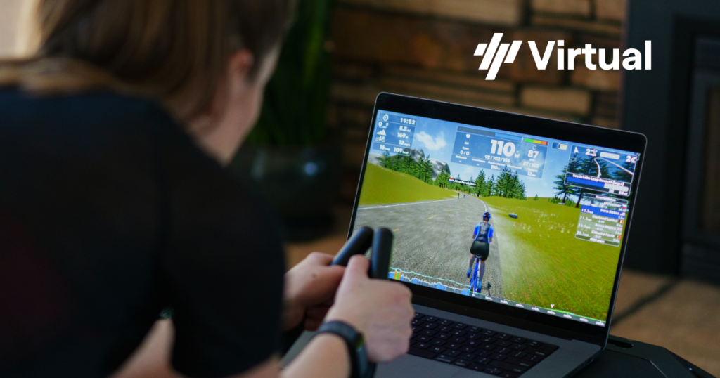 Woman riding indoor cycling trainer with TrainingPeaks Virtual on laptop screen
